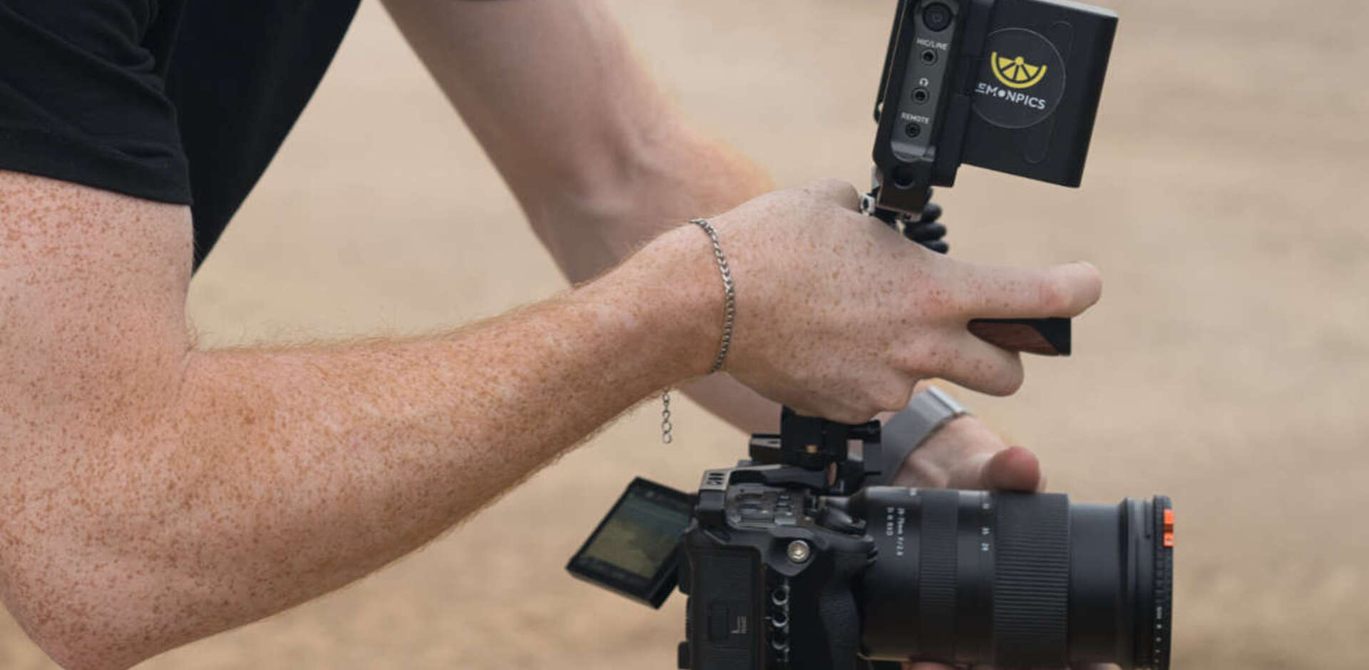 Close-up eines LemonPics Mitarbeiters, der eine professionelle Kamera hält, mit einem LemonPics-Logo auf dem Display.