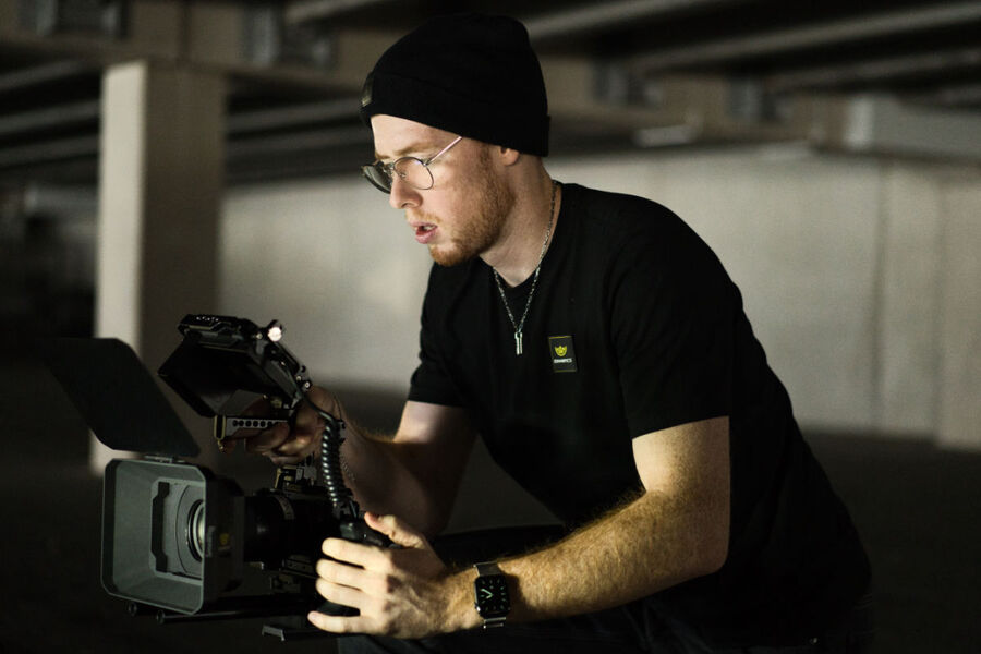 Ein LemonPics Mitarbeiter mit einer schwarzen Mütze konzentriert sich auf die Bedienung einer professionellen Kamera (Sony FX3) in einer Tiefgarage.